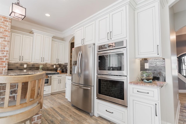 kitchen featuring white cabinetry, crown molding, stainless steel appliances, and decorative backsplash