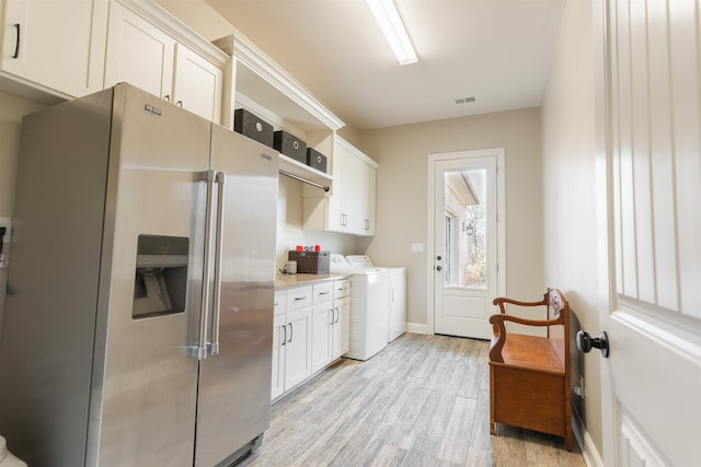 kitchen featuring high end fridge, light stone countertops, light hardwood / wood-style floors, washer and dryer, and white cabinets