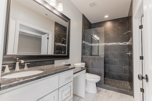 bathroom with vanity, toilet, and a tile shower