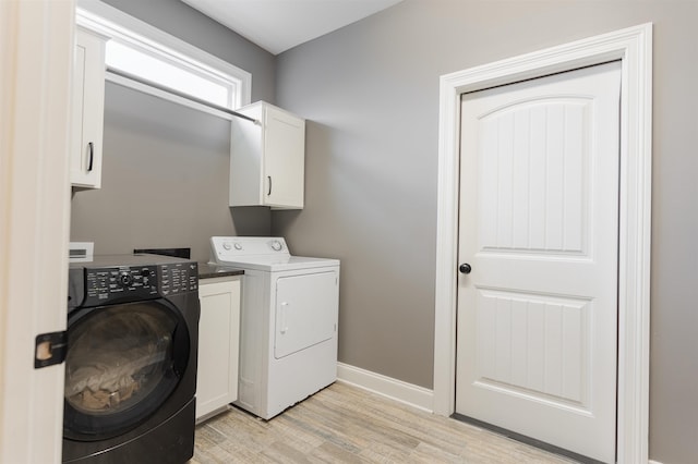 clothes washing area with cabinets, washing machine and clothes dryer, and light wood-type flooring