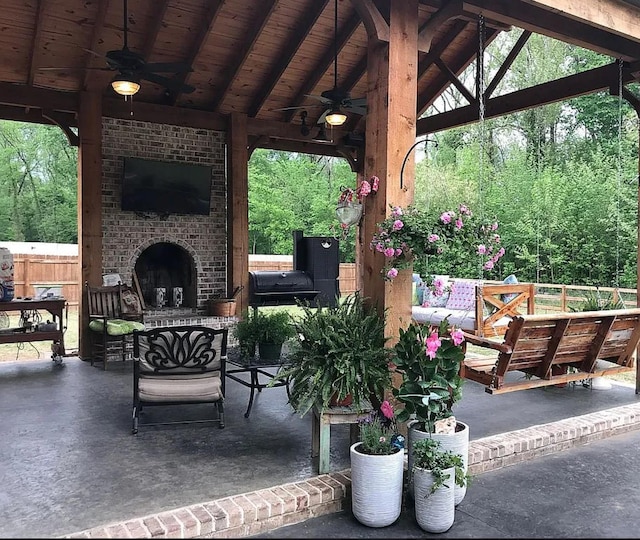 view of patio featuring an outdoor brick fireplace, a gazebo, and ceiling fan