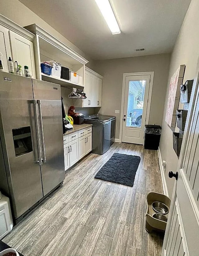 kitchen with white cabinetry, high quality fridge, independent washer and dryer, and light hardwood / wood-style floors