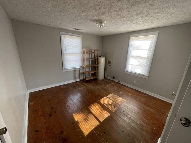 spare room featuring gas water heater, a textured ceiling, and dark hardwood / wood-style flooring