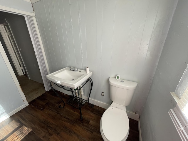 bathroom with sink, wood-type flooring, toilet, and wood walls