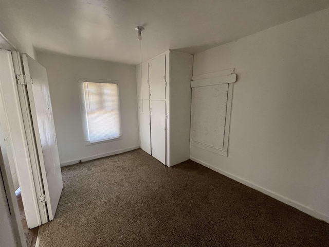 unfurnished bedroom featuring dark carpet and a closet