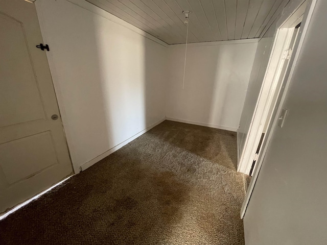 unfurnished room with wood ceiling and carpet flooring