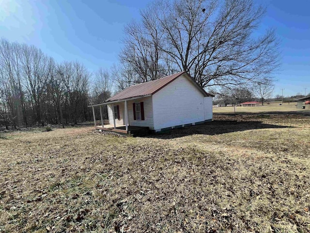 view of side of home featuring covered porch and a lawn