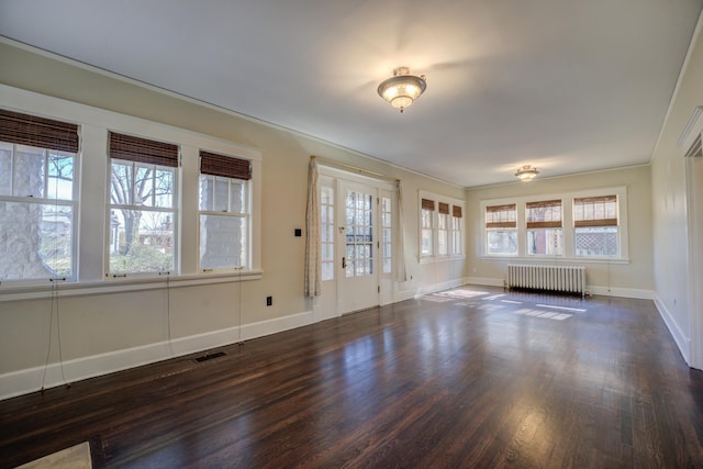 unfurnished room featuring plenty of natural light, dark hardwood / wood-style floors, and radiator