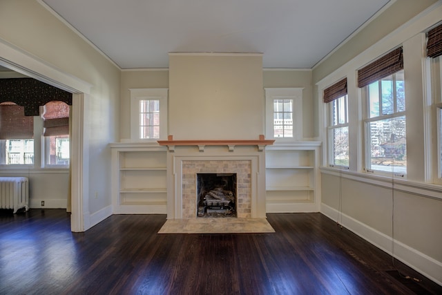 unfurnished living room with a tiled fireplace, radiator, crown molding, and dark wood-type flooring