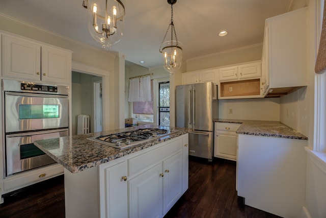 kitchen with stainless steel appliances, white cabinetry, a center island, and decorative light fixtures