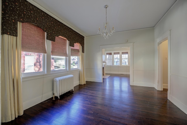 unfurnished room with dark wood-type flooring, ornamental molding, radiator heating unit, and a notable chandelier