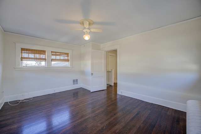 empty room featuring crown molding, dark wood-type flooring, and ceiling fan