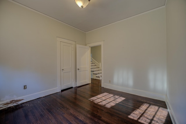 spare room featuring dark wood-type flooring and ornamental molding