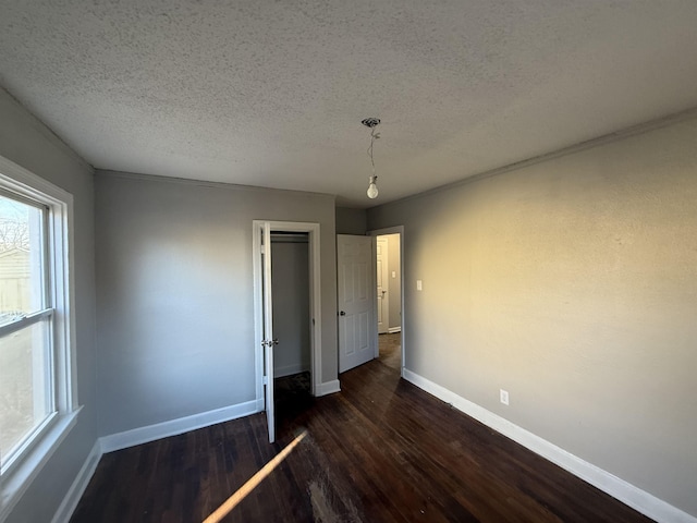 unfurnished bedroom featuring a textured ceiling and dark hardwood / wood-style flooring