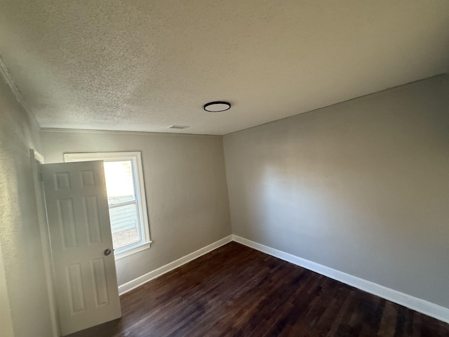 unfurnished room featuring dark wood-type flooring and a textured ceiling