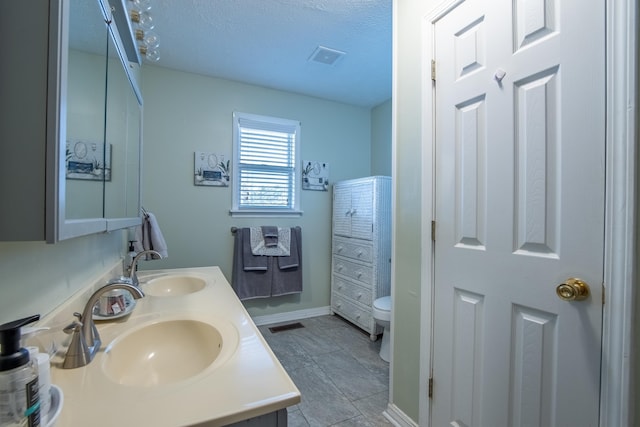 bathroom with vanity, a textured ceiling, tile patterned floors, and toilet