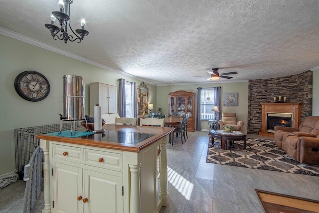 kitchen featuring ornamental molding, a stone fireplace, a center island, and a textured ceiling