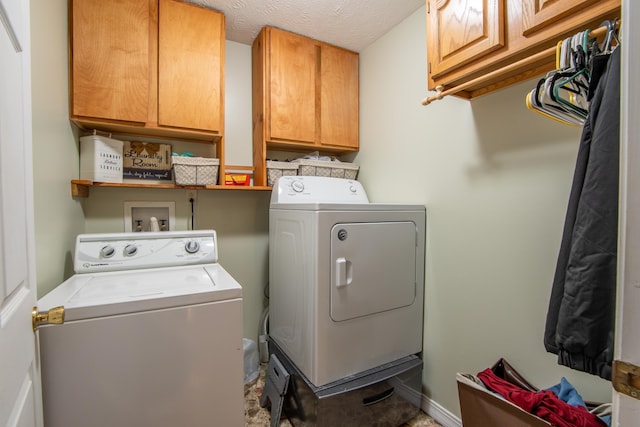 laundry area with cabinets, washer and clothes dryer, and a textured ceiling