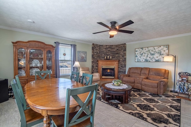 dining space with a fireplace, ornamental molding, light tile patterned floors, ceiling fan, and a textured ceiling