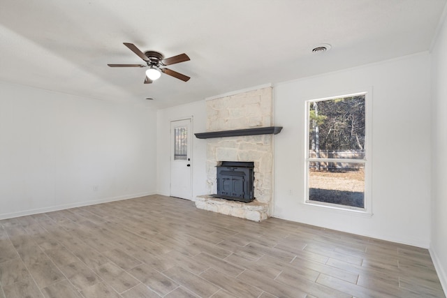 unfurnished living room featuring ceiling fan and a wood stove