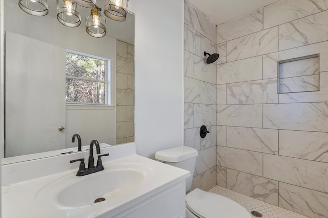 bathroom featuring a tile shower, vanity, and toilet