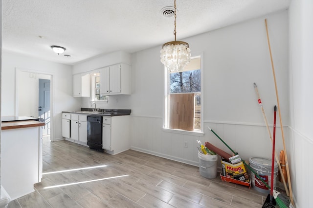 kitchen featuring sink, black dishwasher, a notable chandelier, pendant lighting, and white cabinets