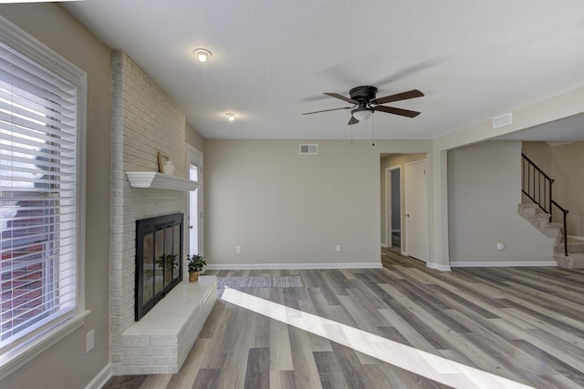 unfurnished living room featuring a textured ceiling, a fireplace, light hardwood / wood-style floors, and ceiling fan