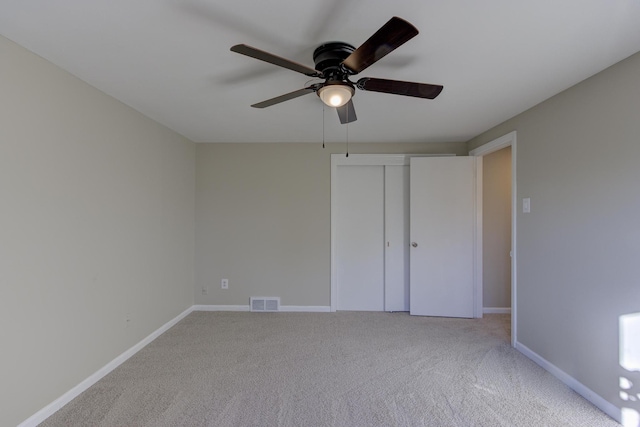 unfurnished bedroom featuring light colored carpet, a closet, and ceiling fan