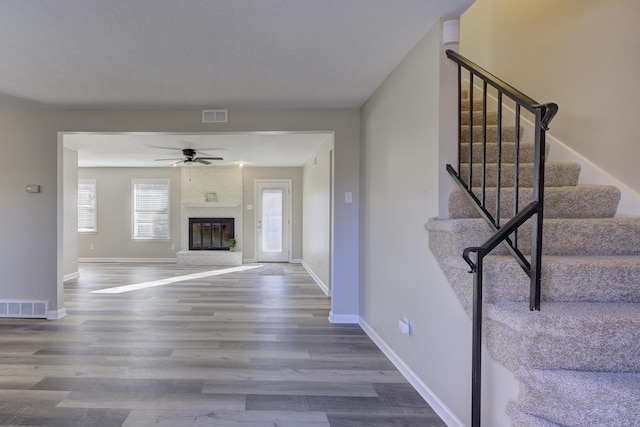 unfurnished living room with hardwood / wood-style flooring, a fireplace, and ceiling fan