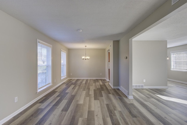 spare room featuring hardwood / wood-style flooring, a notable chandelier, and a textured ceiling