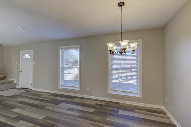 unfurnished dining area with dark wood-type flooring and a notable chandelier