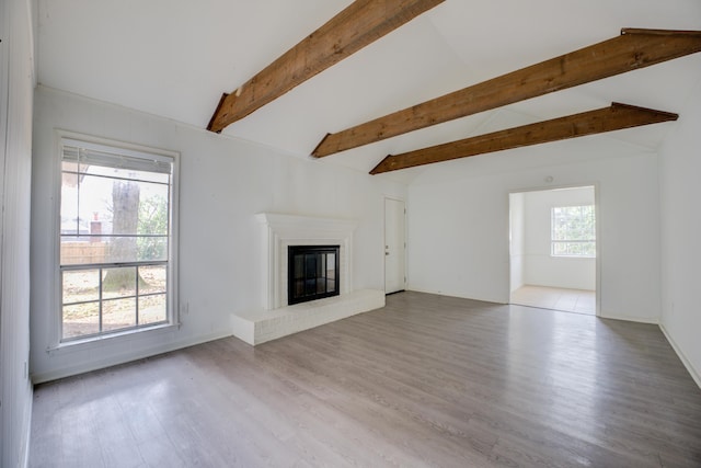 unfurnished living room featuring a fireplace, lofted ceiling with beams, and light wood-type flooring