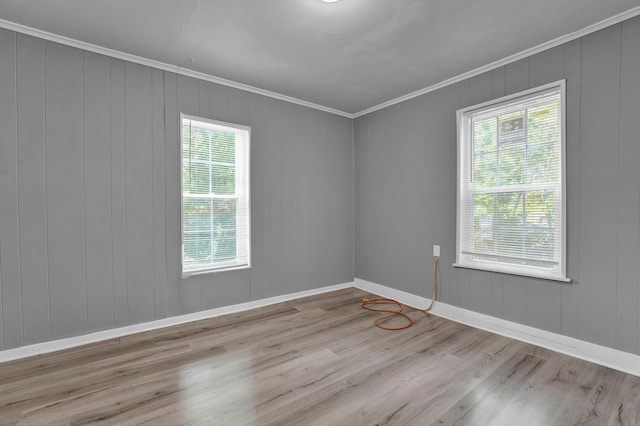 empty room with crown molding, plenty of natural light, and light hardwood / wood-style floors