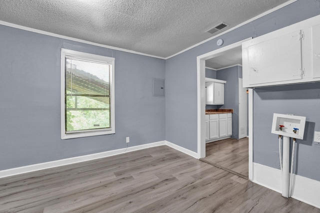 interior space with light hardwood / wood-style flooring, ornamental molding, a textured ceiling, and electric panel