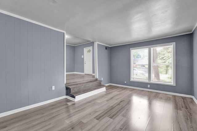 interior space with wooden walls, ornamental molding, and light wood-type flooring