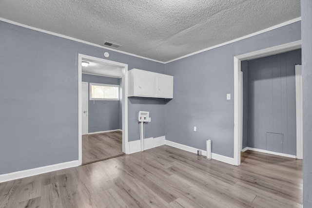 spare room featuring crown molding, a textured ceiling, and light wood-type flooring