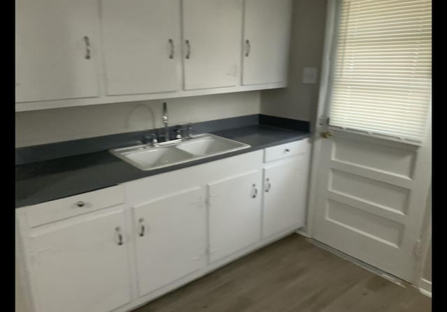 kitchen with white cabinetry, sink, and hardwood / wood-style flooring