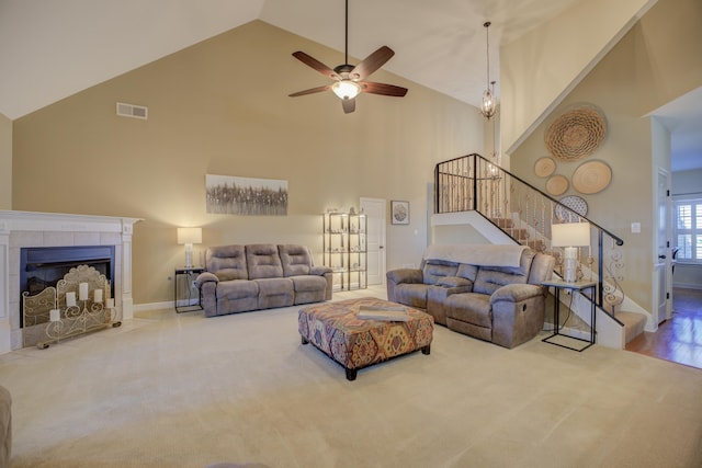 living room with a tile fireplace, carpet flooring, ceiling fan, and high vaulted ceiling