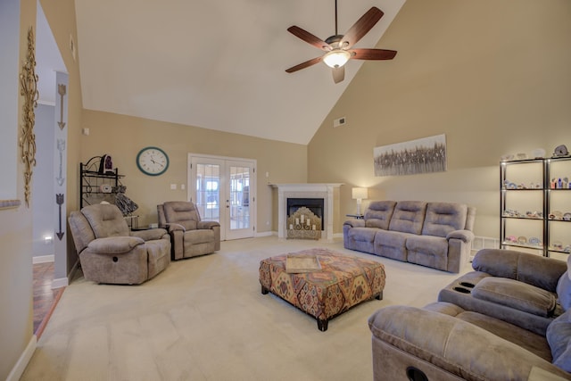 living room with french doors, a towering ceiling, a tiled fireplace, and light carpet