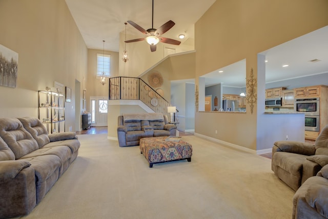 carpeted living room with ceiling fan, a towering ceiling, and crown molding