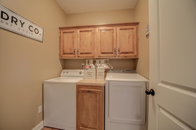 clothes washing area with cabinets and separate washer and dryer