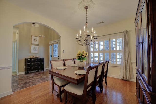 dining space with hardwood / wood-style floors and a notable chandelier