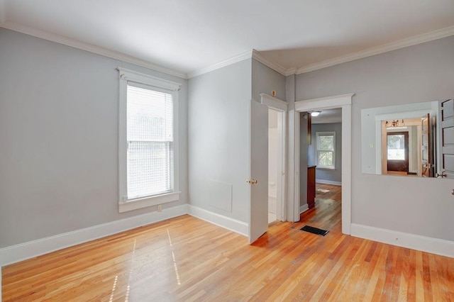 unfurnished room with ornamental molding and light wood-type flooring