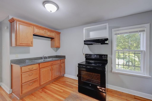 kitchen featuring dark stone countertops, black electric range oven, sink, and light wood-type flooring