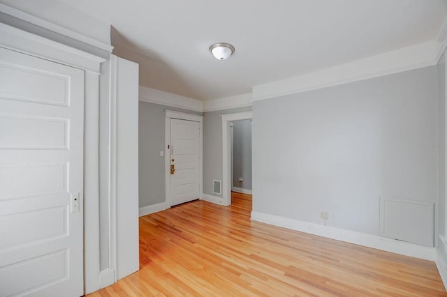 empty room with ornamental molding and light hardwood / wood-style floors