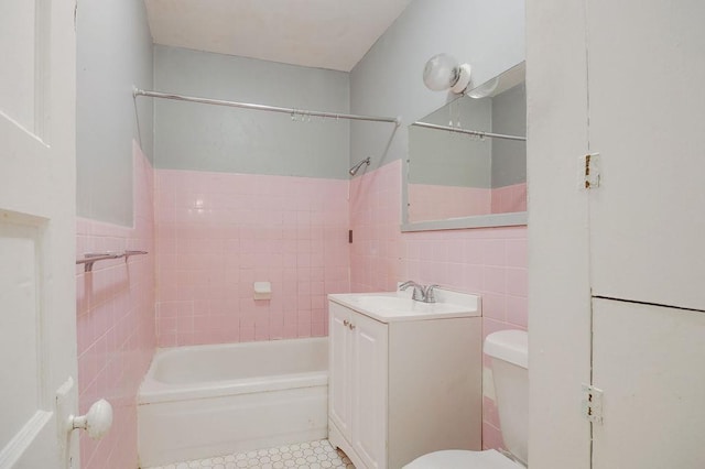 full bathroom with tile walls, vanity, tiled shower / bath combo, and toilet