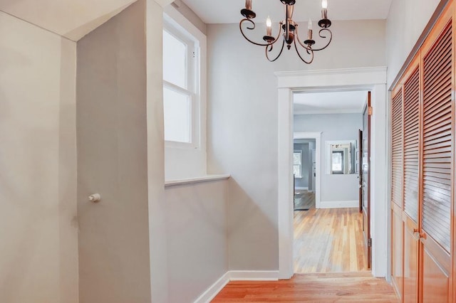 corridor featuring an inviting chandelier and light hardwood / wood-style flooring