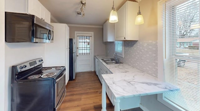 kitchen featuring pendant lighting, sink, appliances with stainless steel finishes, white cabinetry, and decorative backsplash