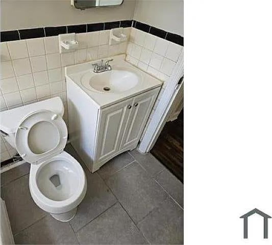 bathroom with tile patterned floors, vanity, toilet, and tile walls