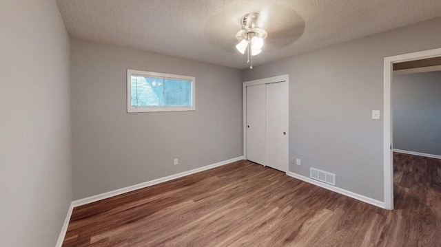 unfurnished bedroom with a textured ceiling, dark hardwood / wood-style floors, a closet, and ceiling fan